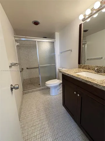 a bathroom with a granite countertop sink toilet and shower