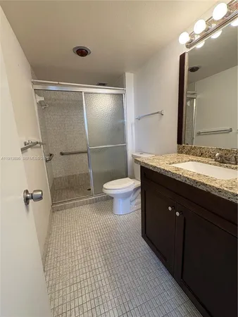 a bathroom with a granite countertop sink toilet and shower