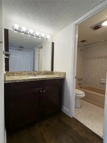 a bathroom with a granite countertop sink a toilet and a large mirror
