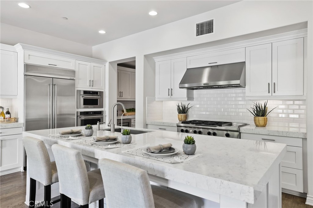 49 Saddlehorn Irvine, CA 92602 - Photo 17 of 73 a kitchen with stainless steel appliances kitchen island granite countertop a stove a sink a refrigerator and white cabinets