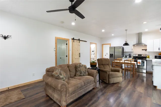 a living room with couches and kitchen view with wooden floor
