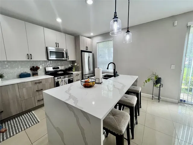 a kitchen with stainless steel appliances a table chairs refrigerator and microwave