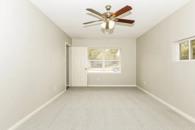 an empty room with a window and a ceiling fan