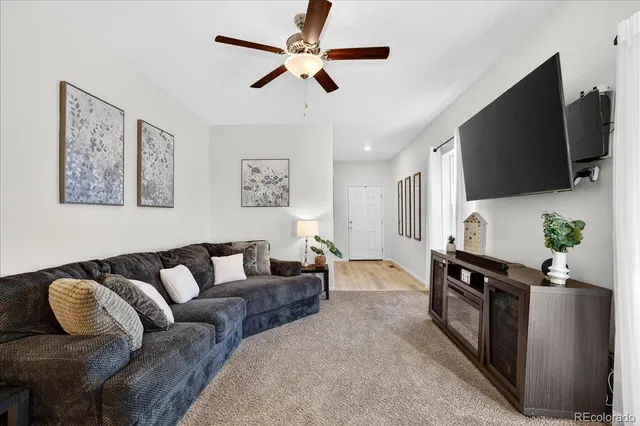 a living room with furniture a flat screen tv and a potted plant