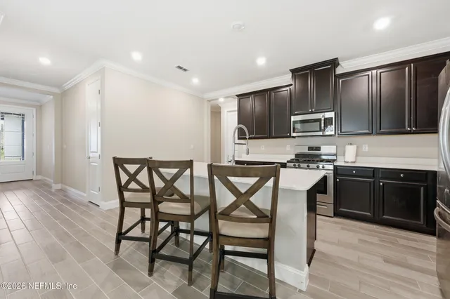 a kitchen with stainless steel appliances kitchen island granite countertop a stove a sink a refrigerator with a dining table and chairs