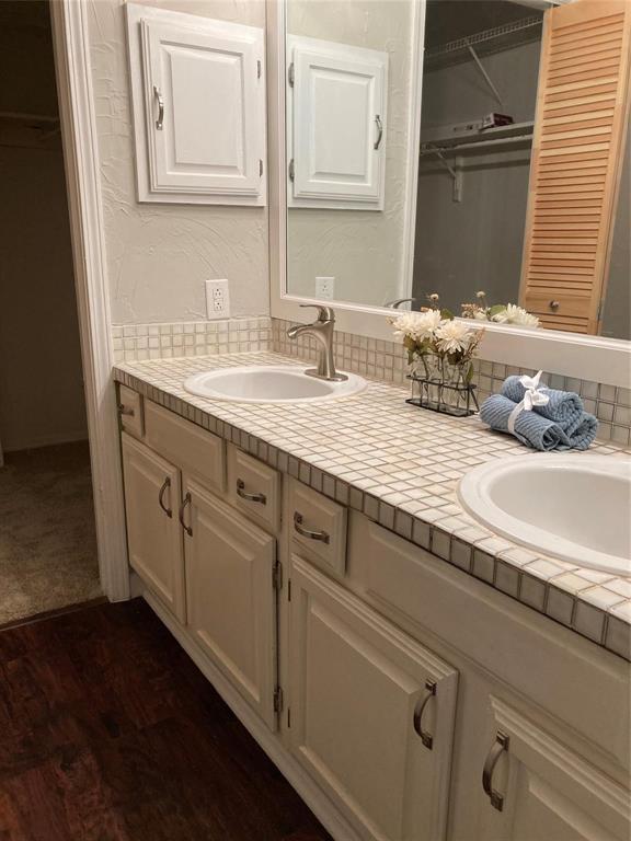 18240 Midway Road, Unit 905 Dallas, TX 75287 - Photo 11 of 15 Full bathroom with double vanity, dark wood-type flooring, a textured wall, and a spacious closet