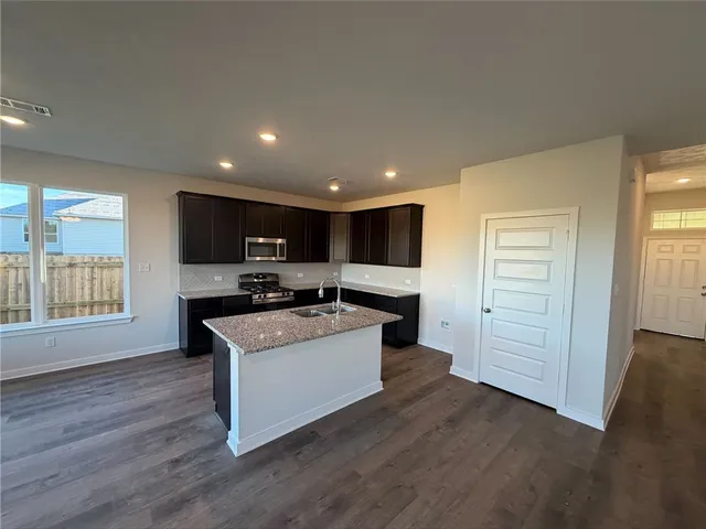 a large kitchen with kitchen island a sink a stove a refrigerator cabinets and living room view