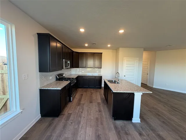 a large kitchen with stainless steel appliances kitchen island a large counter top and a wooden floors