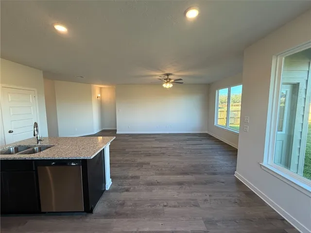 a large kitchen with stainless steel appliances a large counter top a sink and a wooden floor