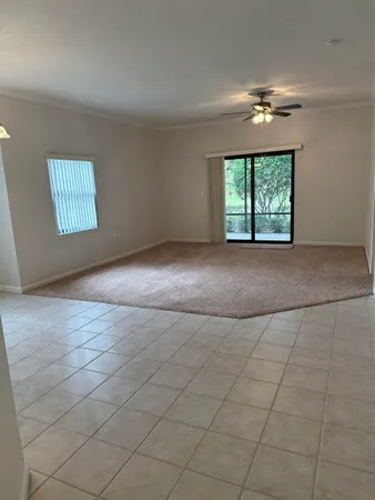 an empty room with windows and chandelier fan