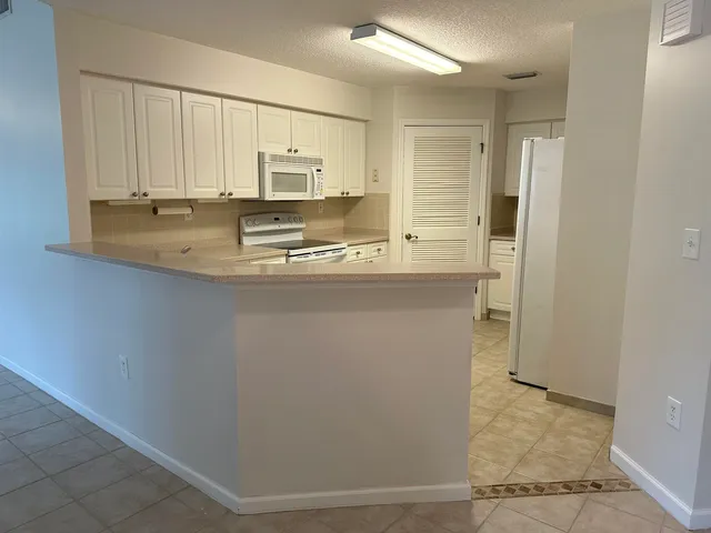 a kitchen with stainless steel appliances granite countertop a refrigerator a stove and white cabinets