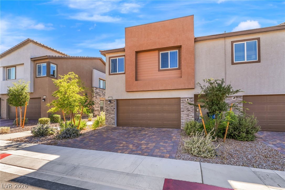 894 Cadence View Way Henderson, NV 89011 - Photo 4 of 23 Modern townhomes feature integrated garages and tasteful landscaping, creating a welcoming facade.