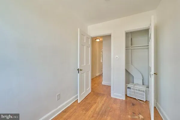 a view of an empty room with wooden floor and a hallway