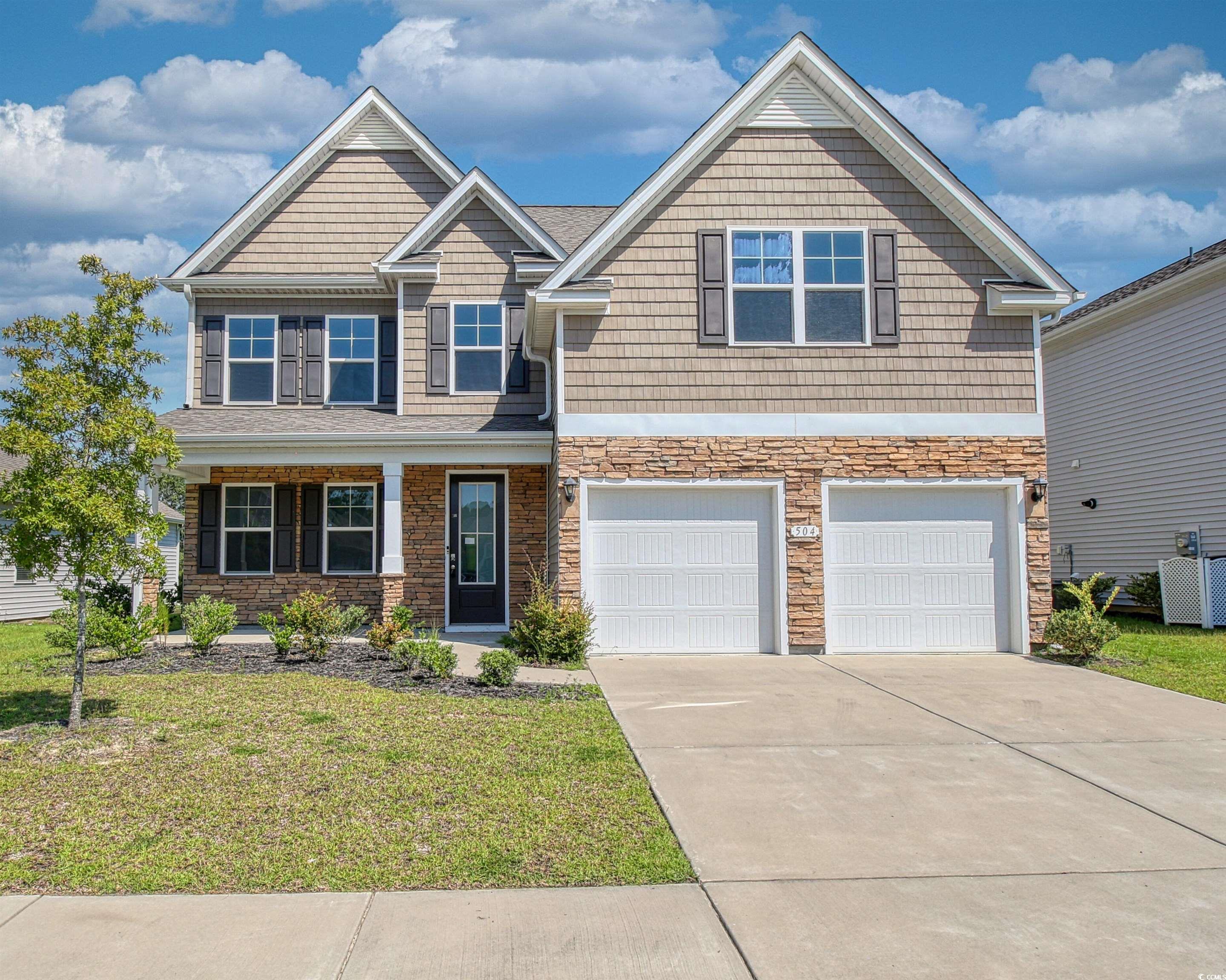 Craftsman house with a garage, a front yard, driveway, and stone siding