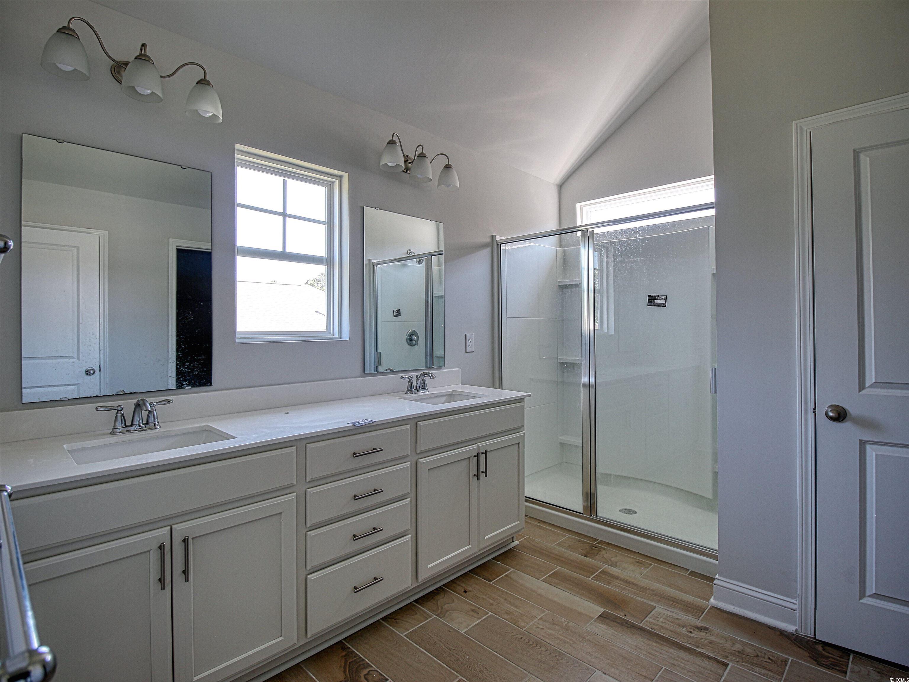 504 Patapsco Street Little River, SC 29566 - Photo 16 of 21 Bathroom featuring double vanity, a stall shower, vaulted ceiling, and wood tiled floors