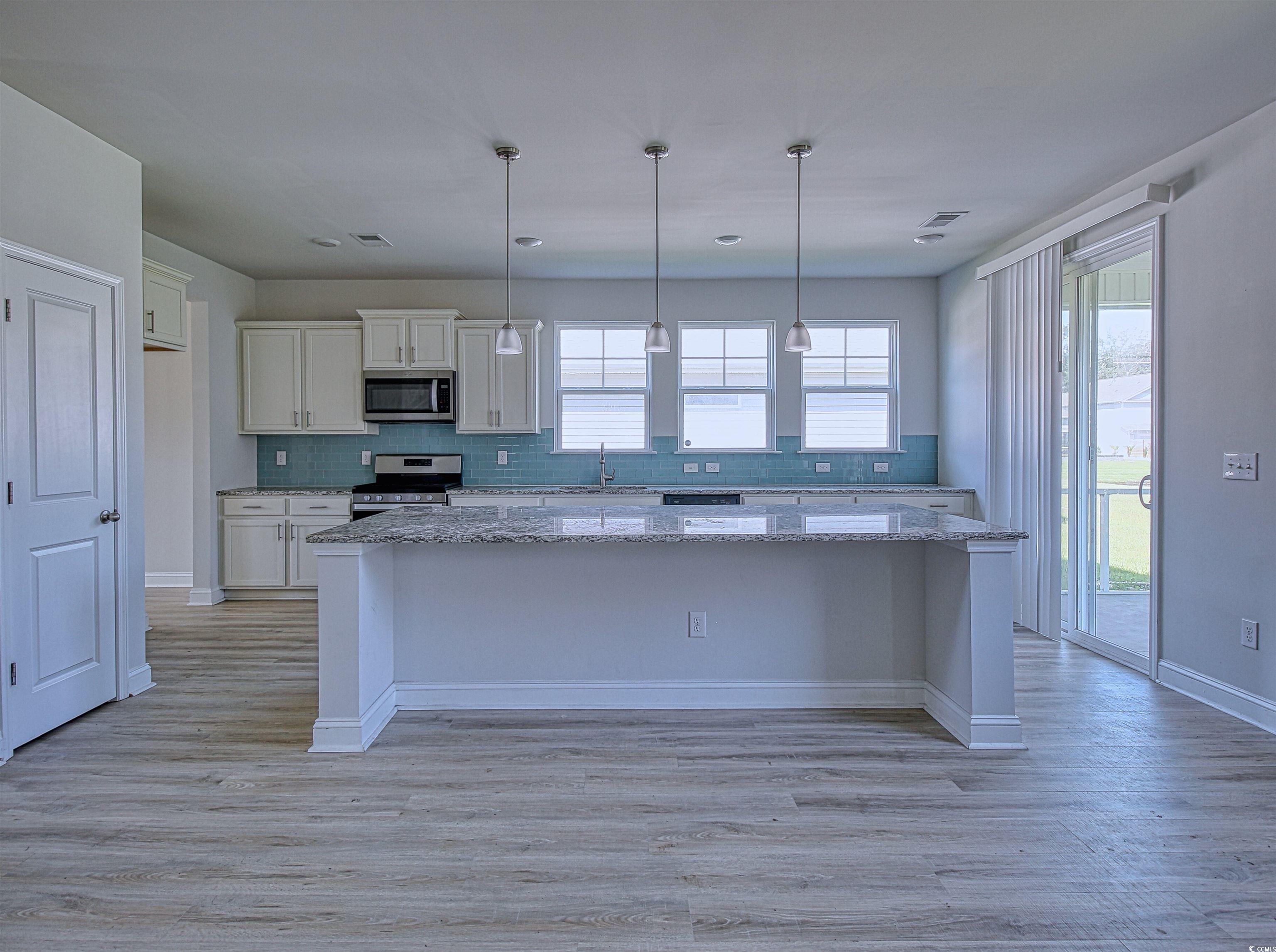 504 Patapsco Street Little River, SC 29566 - Photo 4 of 21 Kitchen with appliances with stainless steel finishes, backsplash, white cabinetry, a center island, and light wood-type flooring