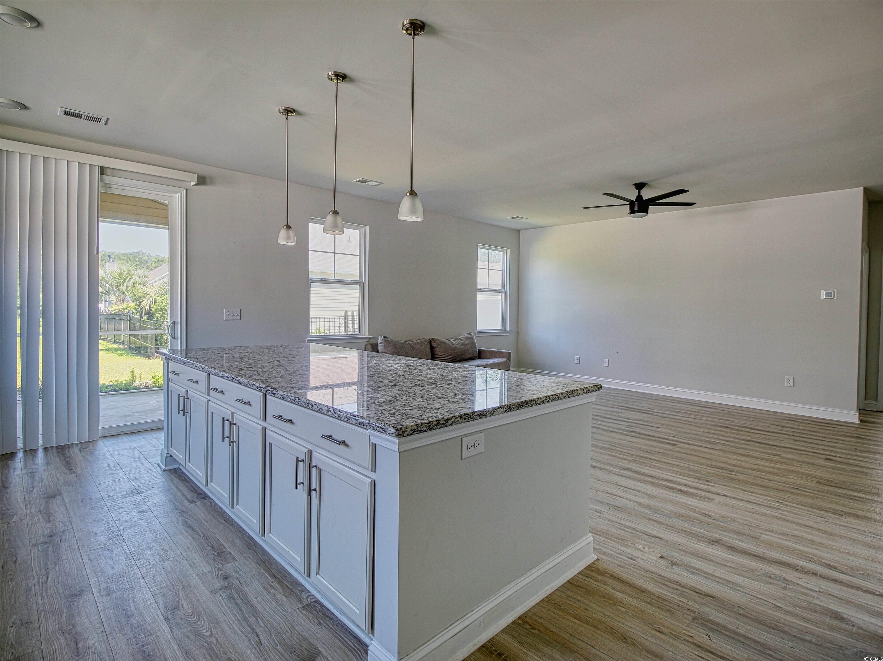 504 Patapsco Street Little River, SC 29566 - Photo 21 of 21 Kitchen with a ceiling fan, wood finished floors, a kitchen island, open floor plan, and light stone countertops