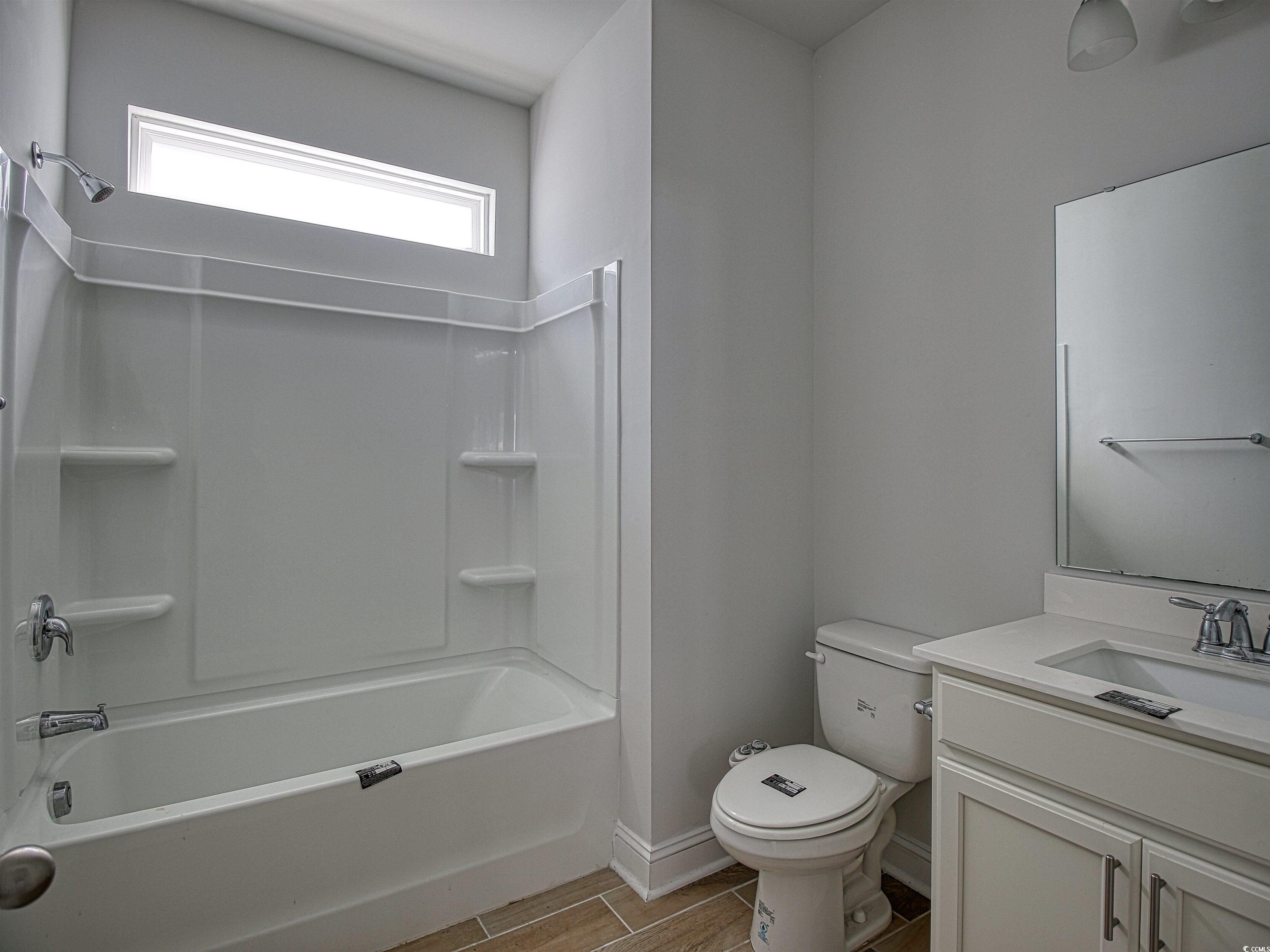 504 Patapsco Street Little River, SC 29566 - Photo 8 of 21 Bathroom featuring wood tiled floors, vanity, and washtub / shower combination