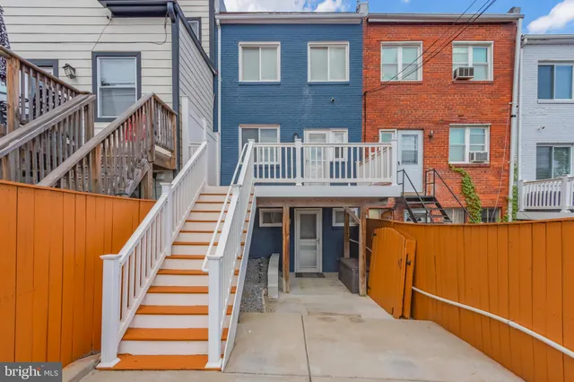 a front view of a house with wooden stairs and a man seat
