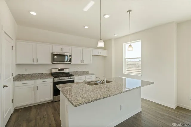 a kitchen with stainless steel appliances granite countertop a sink a stove a refrigerator and white cabinets with wooden floor