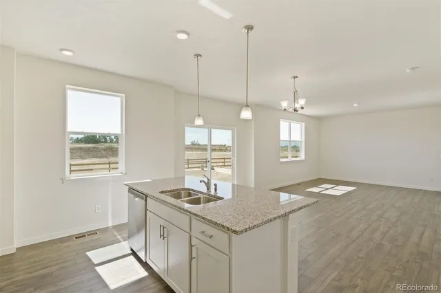 a kitchen with granite countertop a stove a sink a center island and windows