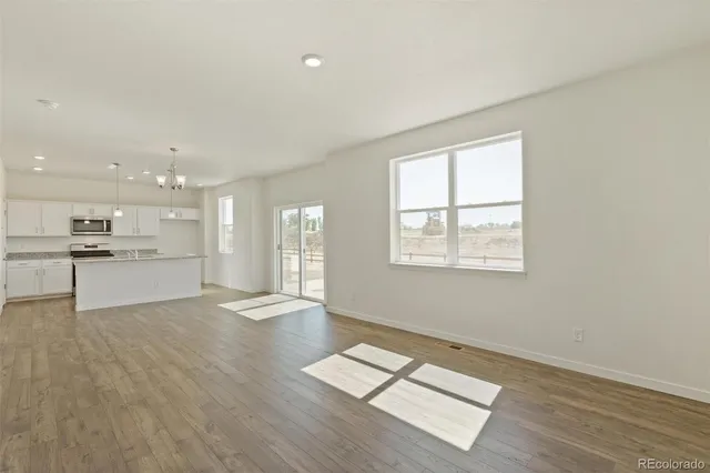 a view of an empty room with kitchen and window