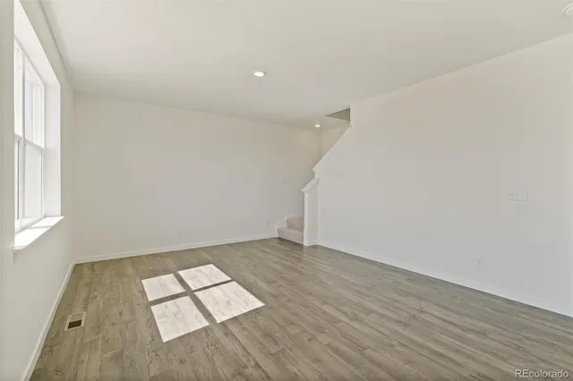 an empty room with wooden floor and windows
