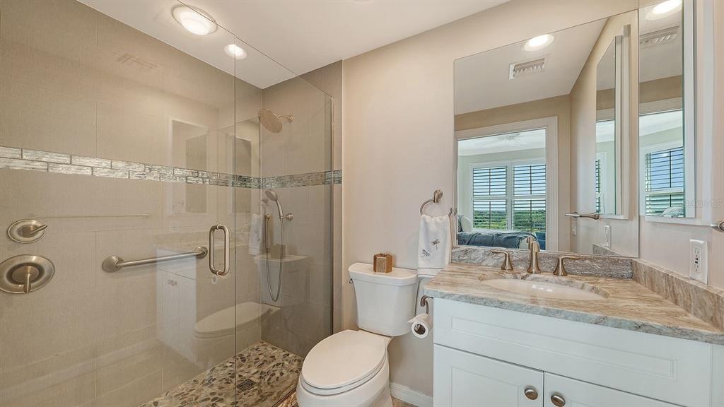 385 North Point Road, Unit 701 Osprey, FL 34229 - Photo 61 of 97 a bathroom with a granite countertop sink toilet a large mirror a shower and a window