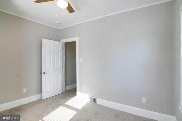 an empty room with ceiling fan and window