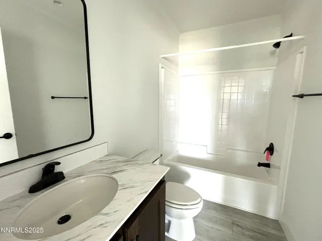 a bathroom with a granite countertop sink a toilet and shower