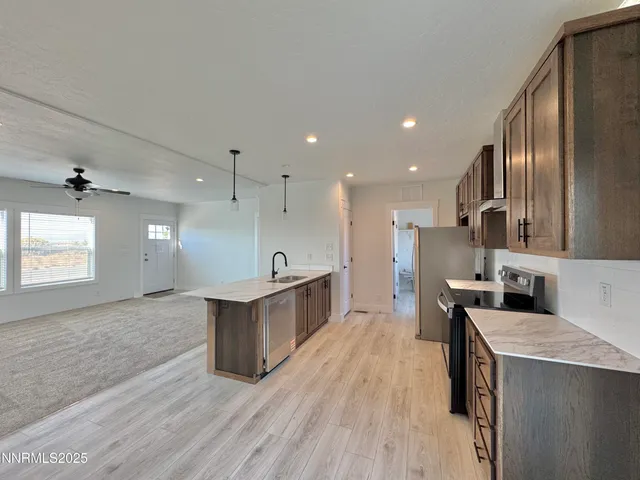 a large kitchen with a center island wooden floor stainless steel appliances and a window