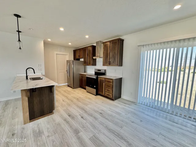 a large kitchen with stainless steel appliances a large counter top a sink and a refrigerator