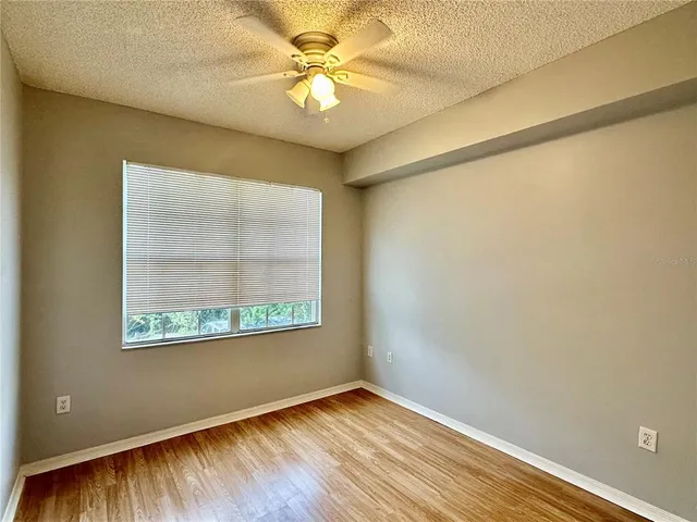a view of empty room with wooden floor and fan