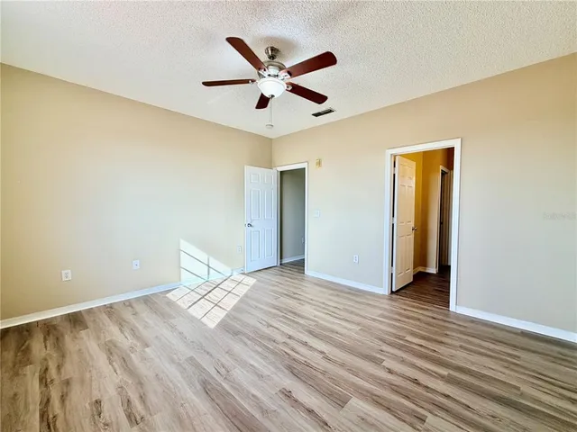 a view of empty room with wooden floor and fan