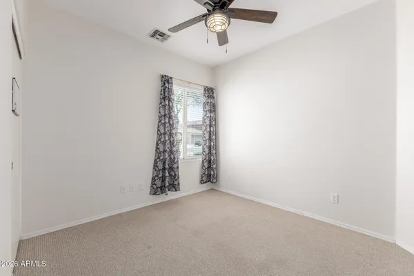 an empty room with a ceiling fan and carpet