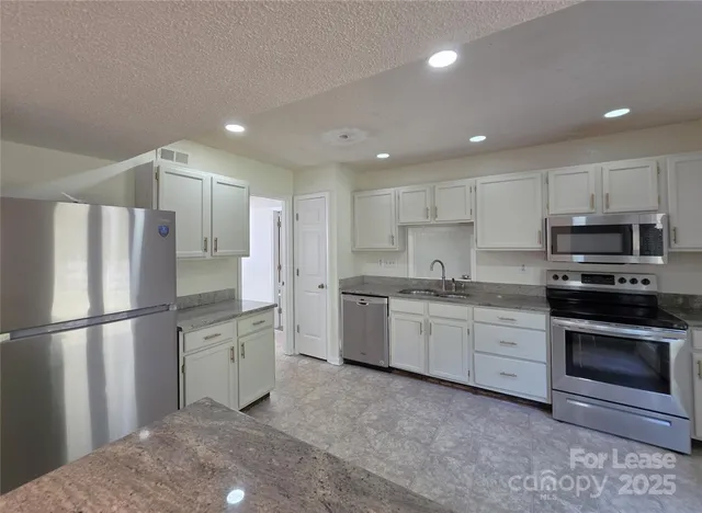 a kitchen with granite countertop stainless steel appliances and refrigerator