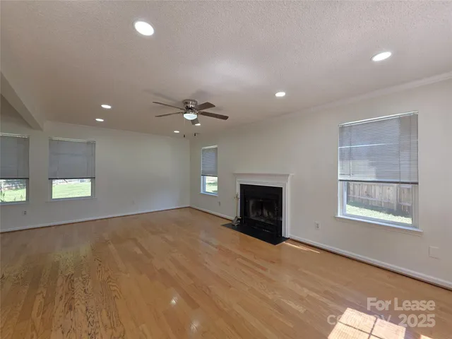 an empty room with windows and fireplace