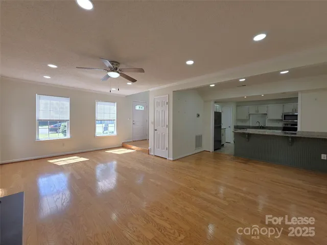 a view of an empty room with window and wooden floor
