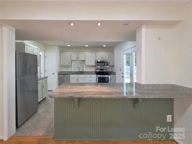 a kitchen with stainless steel appliances granite countertop a refrigerator a sink and a stove