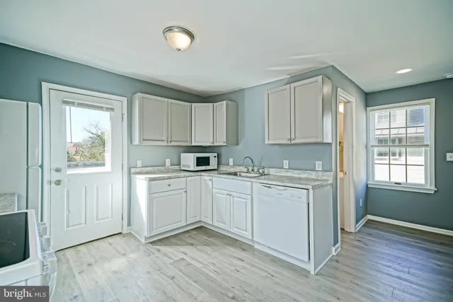 a kitchen with granite countertop white cabinets and white appliances