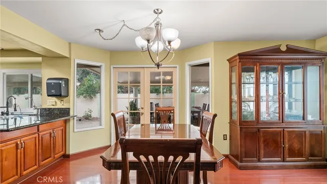 a dining room with wooden floor a chandelier a wooden table and chairs