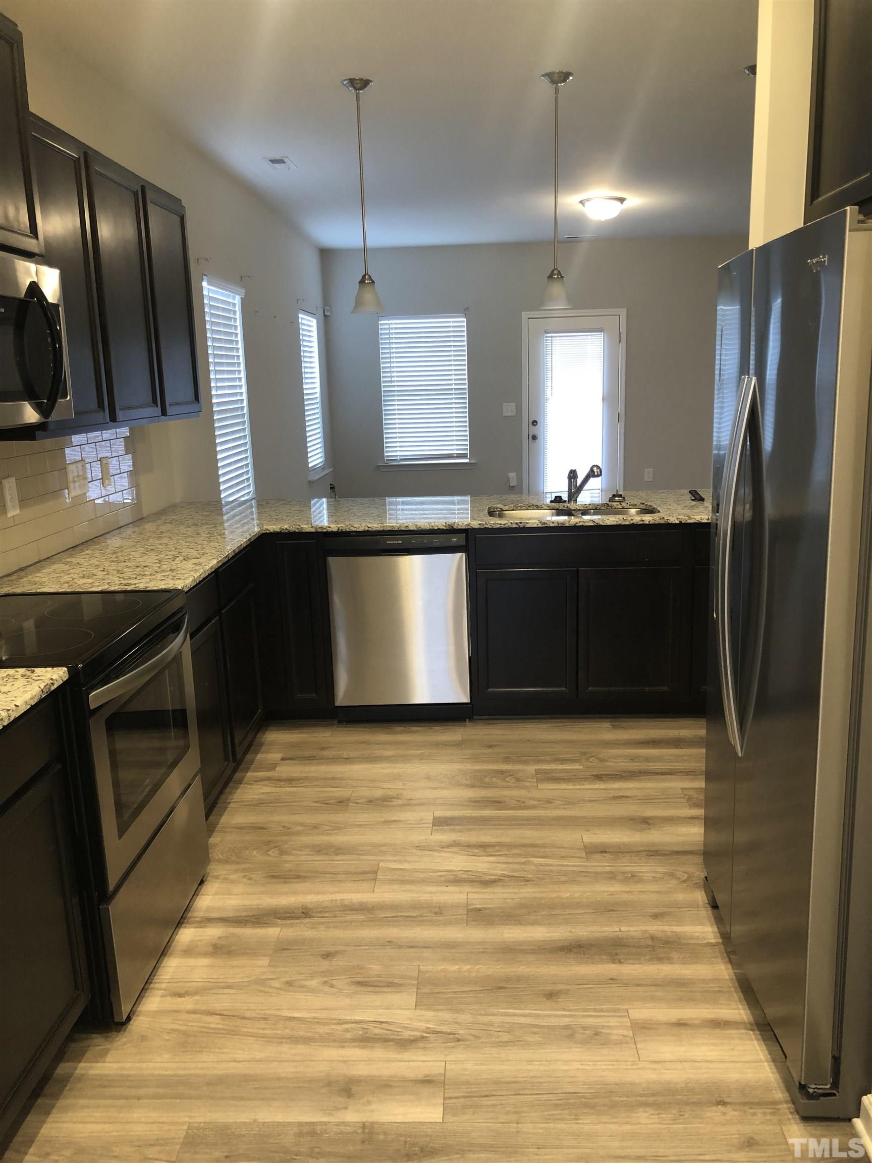 6830 Resting Grove Road Raleigh, NC 27610 - Photo 5 of 20 a large kitchen with granite countertop a refrigerator and a stove top oven