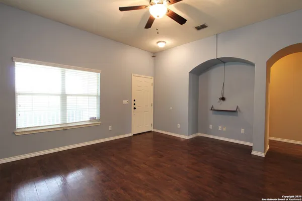 a view of an empty room with wooden floor and a window