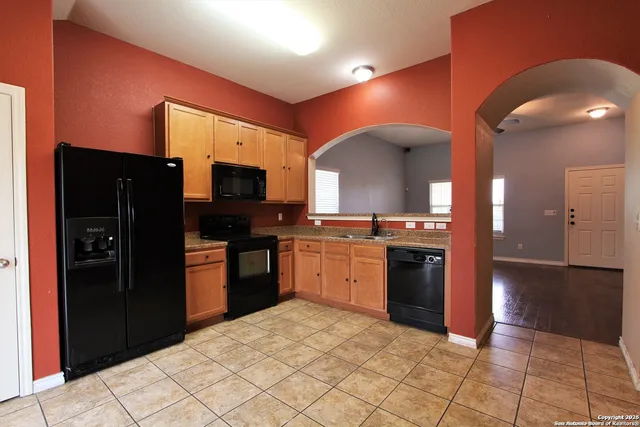 a kitchen with granite countertop a refrigerator and a stove top oven