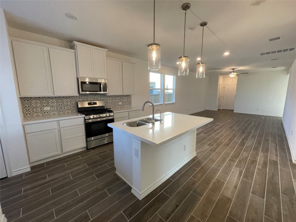 101 Thurman Holt Road Hutto, TX 78634 - Photo 27 of 38 a kitchen with stainless steel appliances granite countertop a sink a stove and a wooden floors