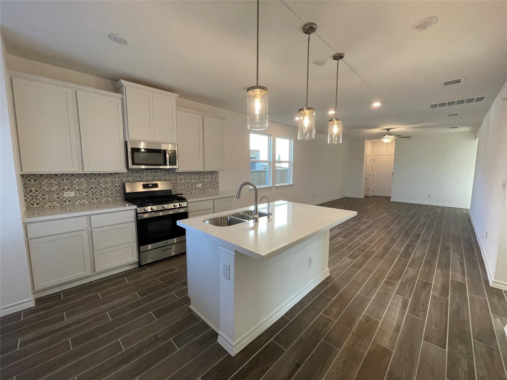 101 Thurman Holt Road Hutto, TX 78634 - Photo 28 of 38 a kitchen with kitchen island granite countertop a sink a counter space appliances and cabinets