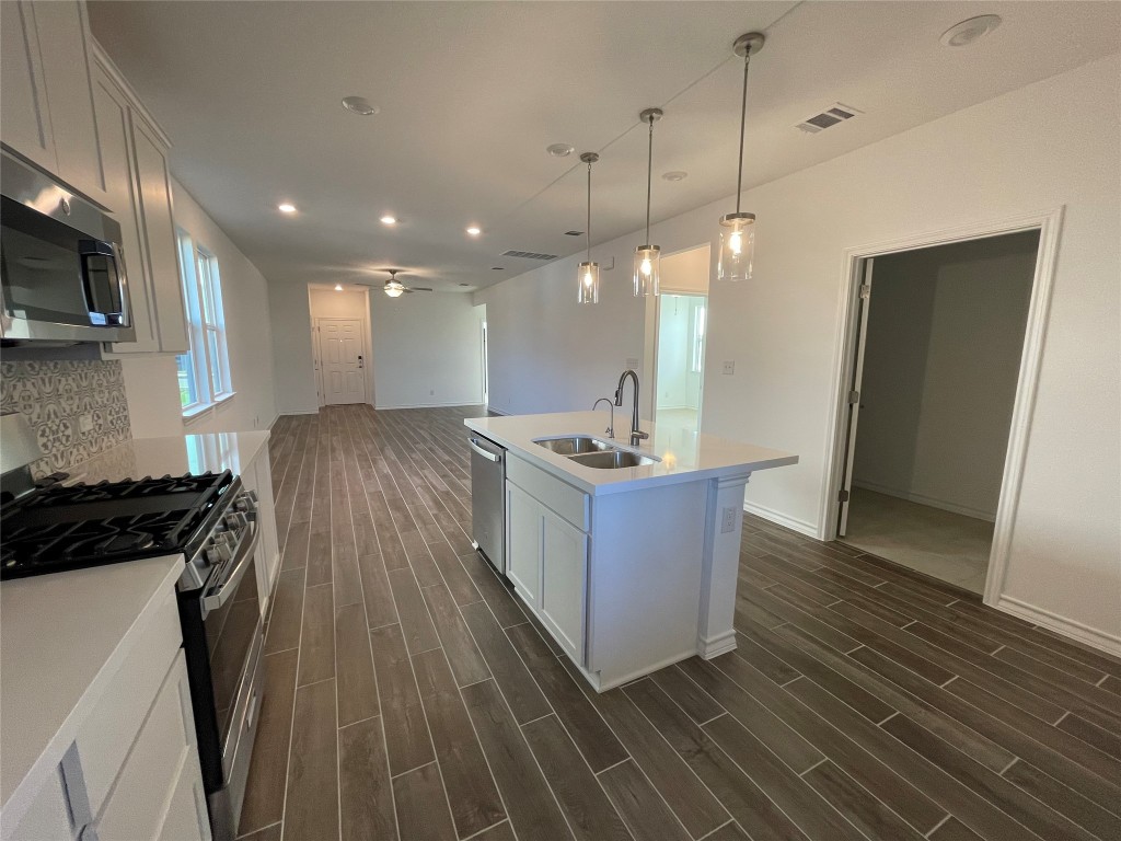 101 Thurman Holt Road Hutto, TX 78634 - Photo 37 of 38 a kitchen with stainless steel appliances granite countertop a stove a sink a refrigerator and a microwave
