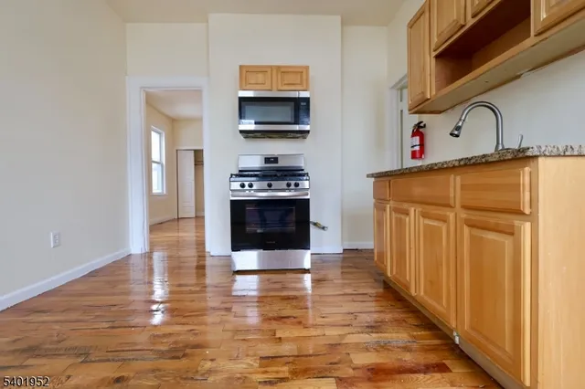 a kitchen with stainless steel appliances granite countertop a stove top oven a sink and a refrigerator