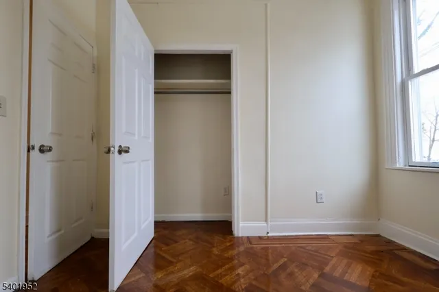 a view of an empty room with window and wooden floor