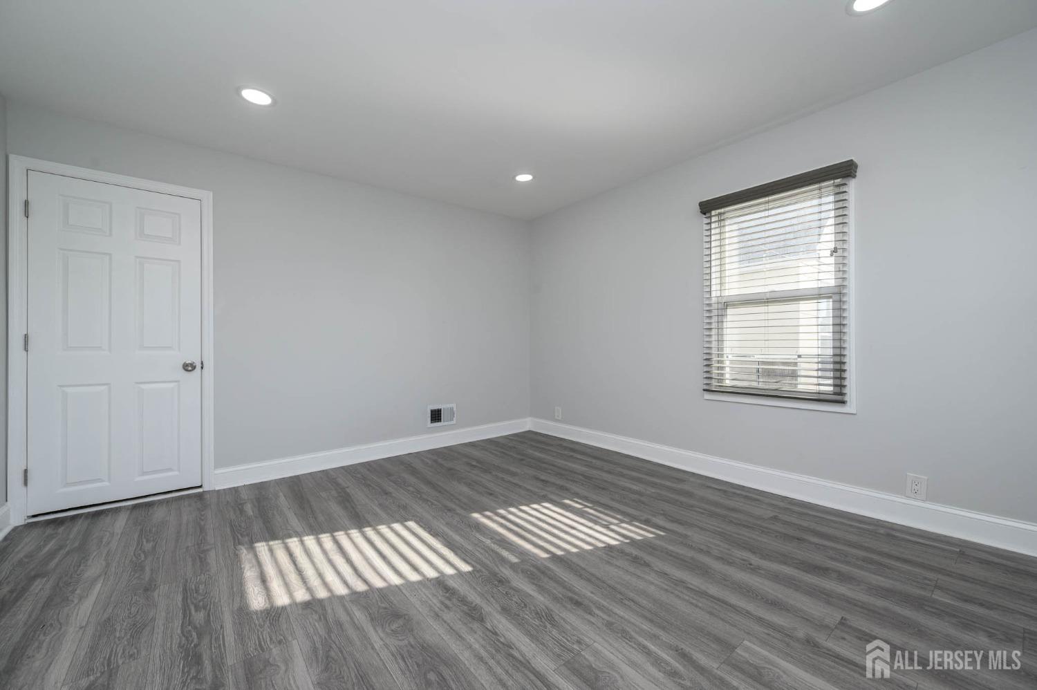 32 Lee Street Port Reading, NJ 07064 - Photo 20 of 32 a view of an empty room with wooden floor and a window